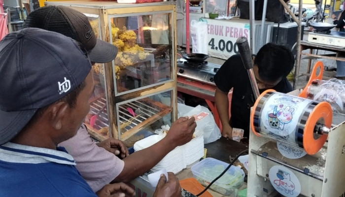 TUKAR. Wahed (46), seorang abang becak, menukarkan kupon takjil dari PWRI Sumenep kepada pedagang di kawasan Tajamara, Sumenep, untuk mendapatkan menu berbuka puasa saat Ramadan. (redaksi/estoria)